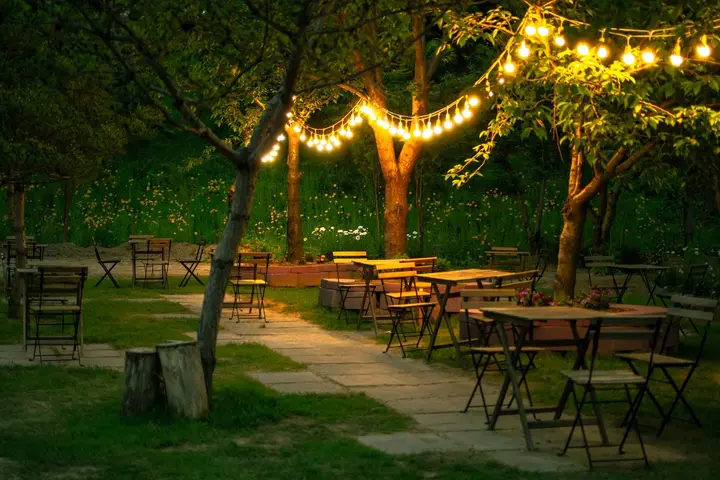 Ogródek restauracyjny z girlandą lampek wieczorem