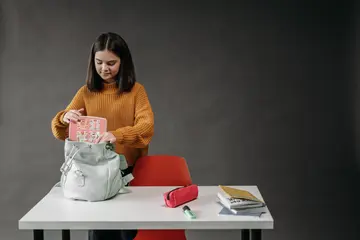 Dziewczyna pakuje plecak szkolny przy biurku