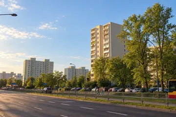 Bloki na Ursynowie wiosną, para idzie chodnikiem wzdłuż ulicy