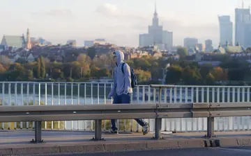 Chłopiec z plecakiem na moście nad Wisłą, w tle centrum Warszawy